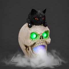 Black cat skull resin figure on a dark background, side view, with the mist spread across the surface below it