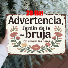 Hand holding the bruja garden sign in front of frosted pine branches