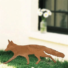 Side view of the metal fox garden ornament standing in grass by a window
