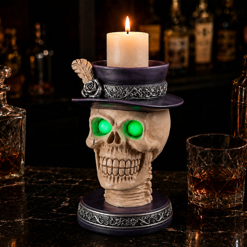 Feather hat skull candle holder with a lighted pillar candle, standing on a bar shelf beside glasses