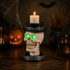 The same skull candle holder from a second angle with the green eye lights on in a dim room