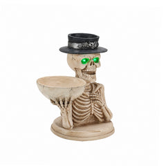 Skeleton candy bowl statue on a plain background, side view, showing the shallow bowl held forward
