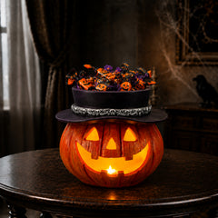 Witch hat pumpkin LED candy bowl filled with chocolates on a dark table, with the jack o lantern face lit from inside