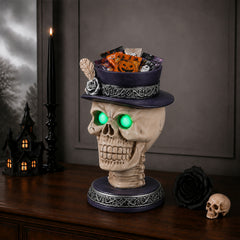 The same feather hat skull candle holder from a second angle with green eye lights in a dim room