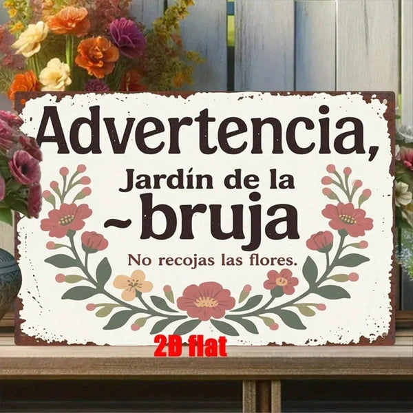 Distressed white garden sign reading Advertencia Jardin de la Bruja on a bench with flowers