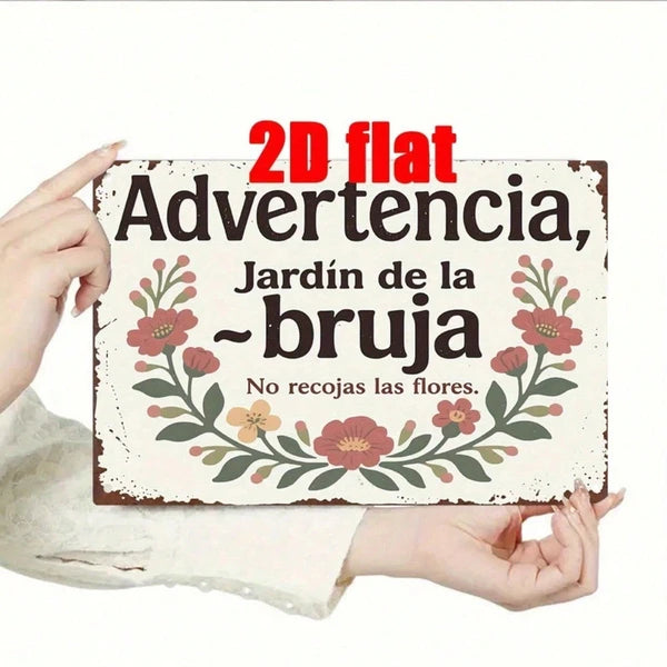 Two hands holding the Advertencia jardin de la bruja metal sign