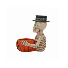 Skeleton candy bowl resin figure on a plain background, side view, with the pumpkin bowl lifted off and set beside it