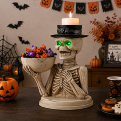 The same skeleton server statue on a sideboard with a carved pumpkin and purple light behind it