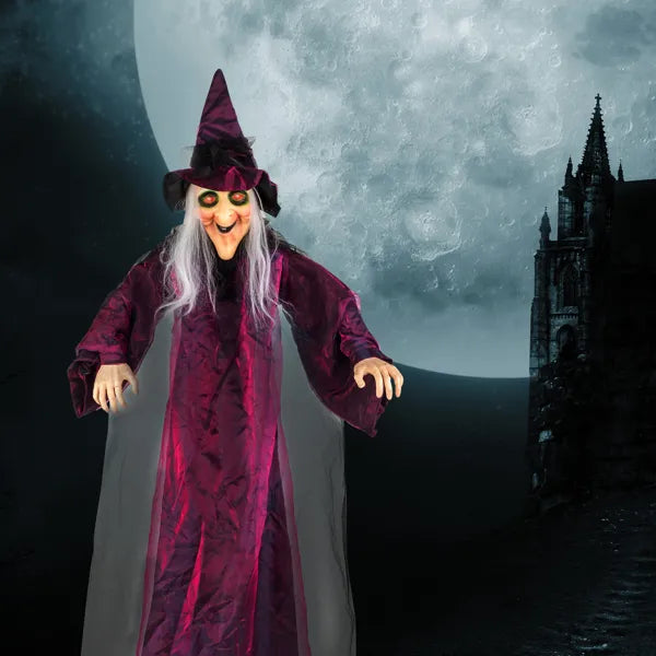 Life size hanging witch decoration with glowing eyes in front of a full moon