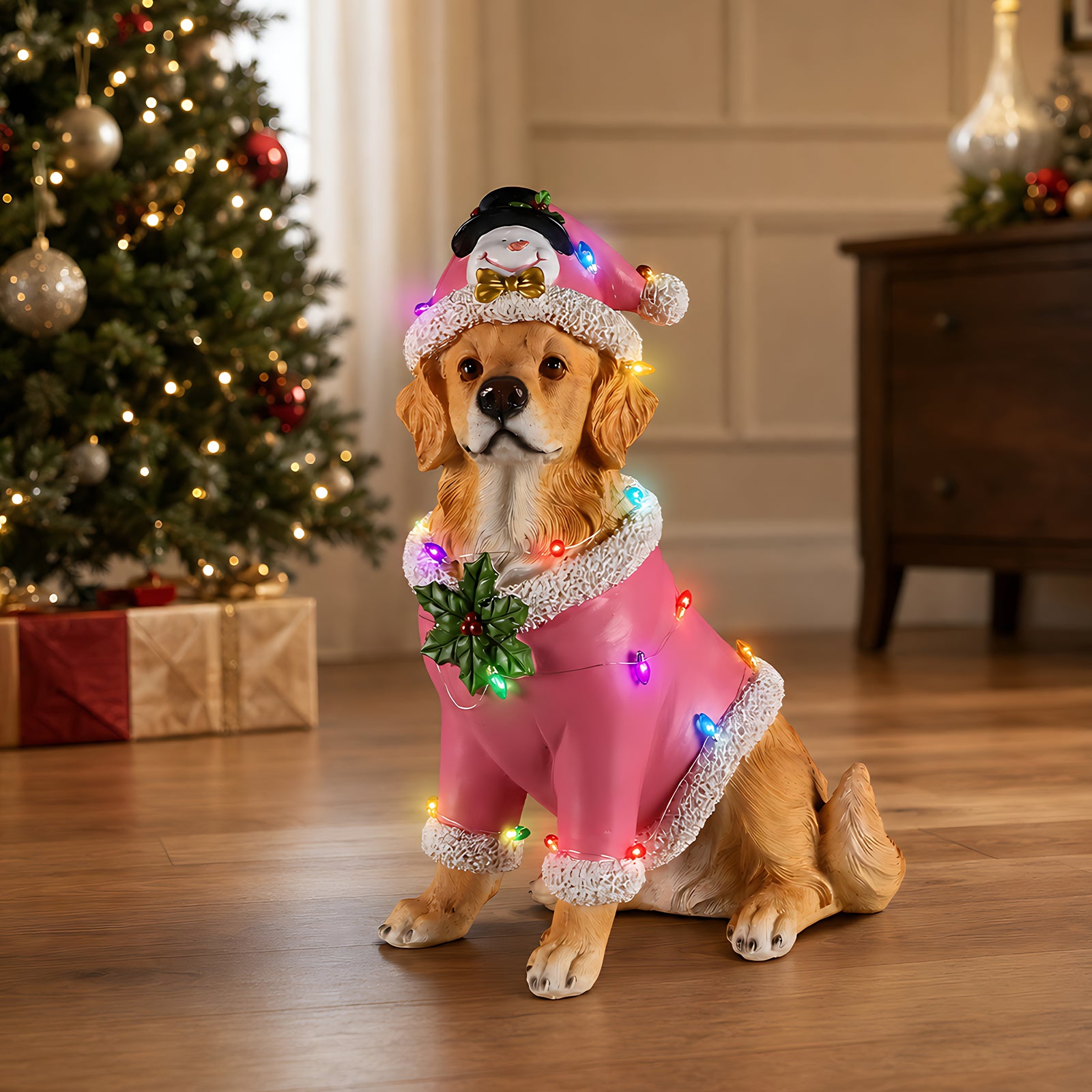 A golden retriever sitting in a pink Santa coat with a string of colored lights across the back, in a living room at Christmas