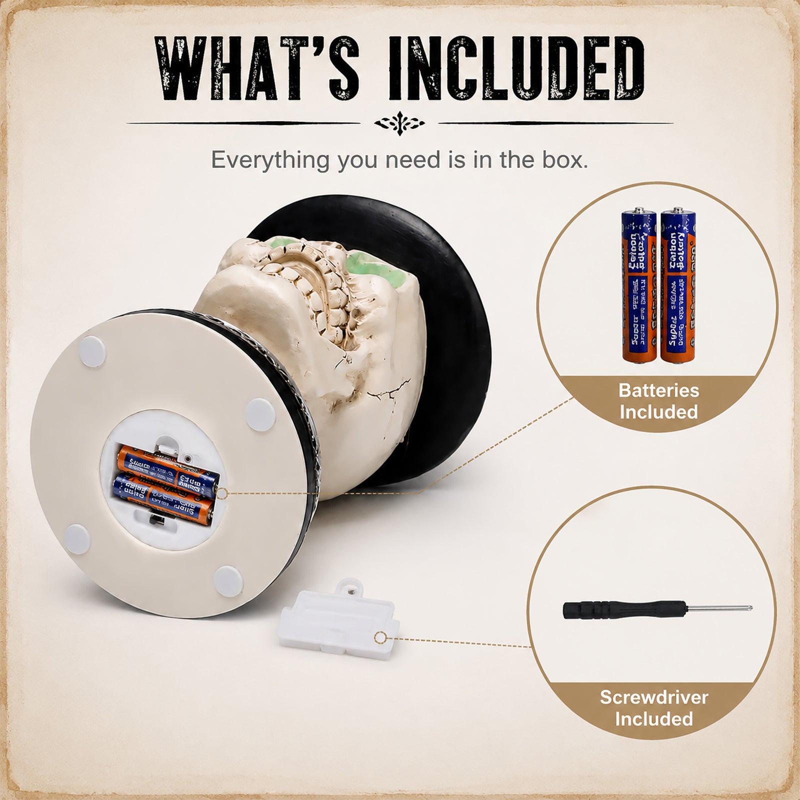 printed card showing what is in the box: the statue lying on its back with the battery compartment in the base open, plus the spare batteries and the small screwdriver