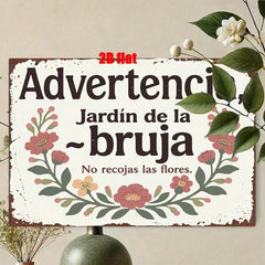 The witch garden sign hung on a wall beside dried flowers and a green vase