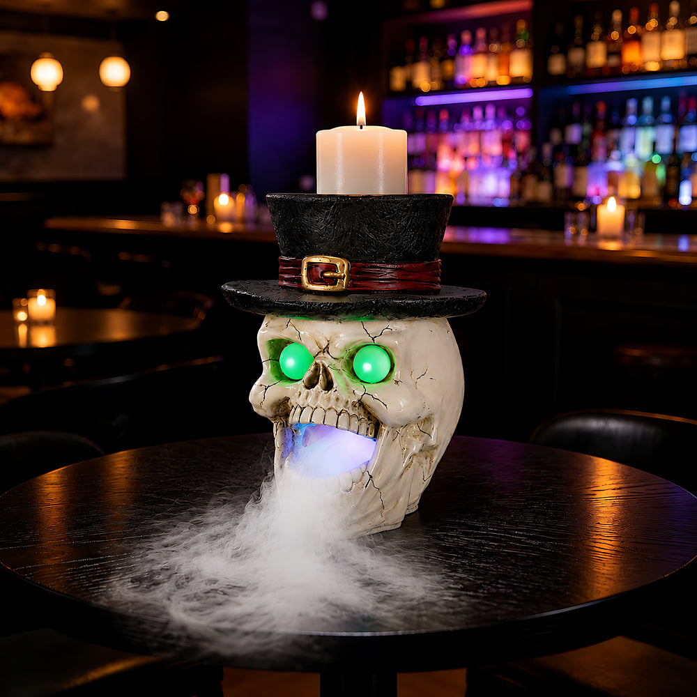 Top hat skull fogger with a pillar candle standing in the hat, on a dark table at night with mist around the base