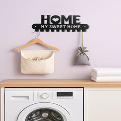 Keys and a small pouch hung on the black HOME wall hooks beside a coat rack