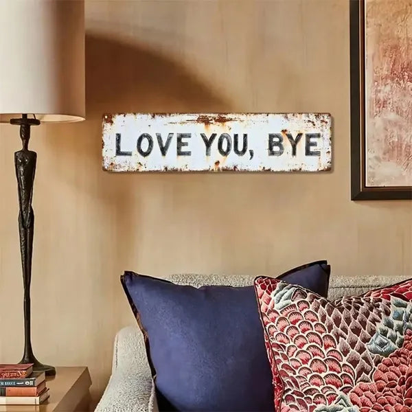 Rustic LOVE YOU BYE metal sign hung on a living room wall above cushions