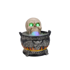 Skull cauldron light up decor on a plain background, turned three quarters to show the cracked skull leaning over the rim