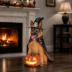The same German shepherd witch statue in front of a lit fireplace, the pumpkin glowing on the hearth