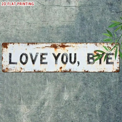LOVE YOU BYE tin sign on a gray concrete wall with bamboo leaves