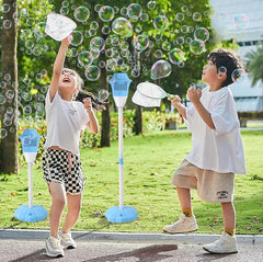Two children blowing bubble wands beside a blue bubble torch lamp on a summer lawn